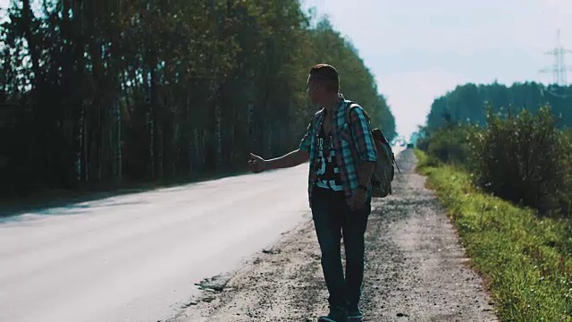 心烦意乱的男人背着背包走在路上。搭便车。拇指。旅行者视频素材画面3