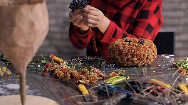 花商在木桌上制作花朵、浆果的组合视频素材画面1
