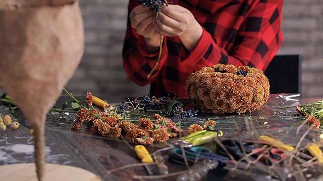 花商在木桌上制作花朵、浆果的组合视频素材画面2