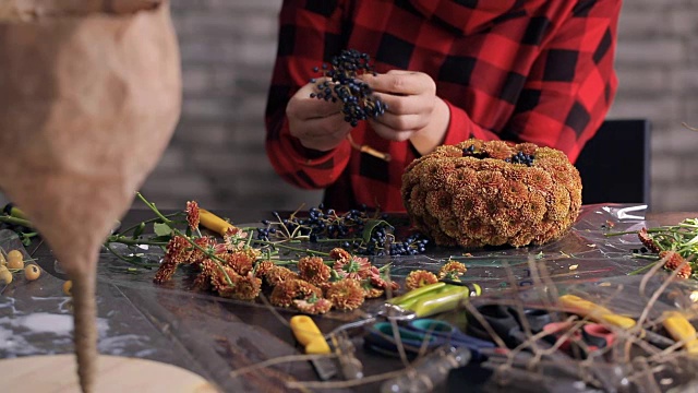 花商在木桌上制作花朵、浆果的组合视频素材画面3