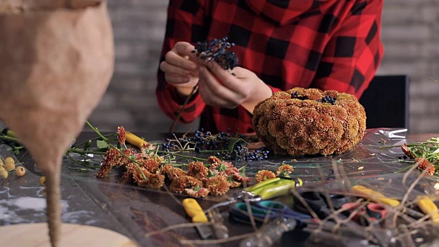 花商在木桌上制作花朵、浆果的组合视频素材画面4