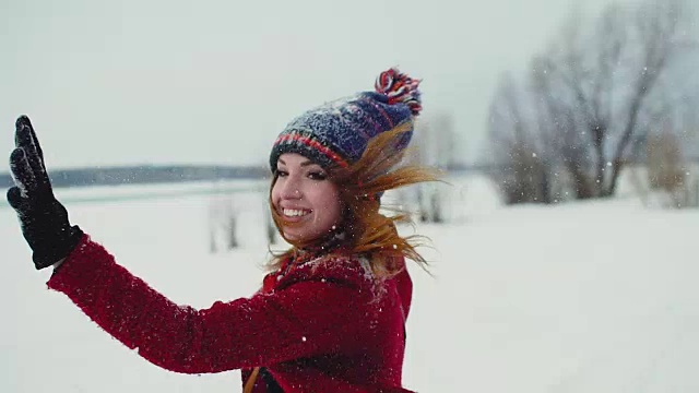 年轻的红发女子在户外享受降雪，笑着看着镜头，慢动作120帧/秒视频素材