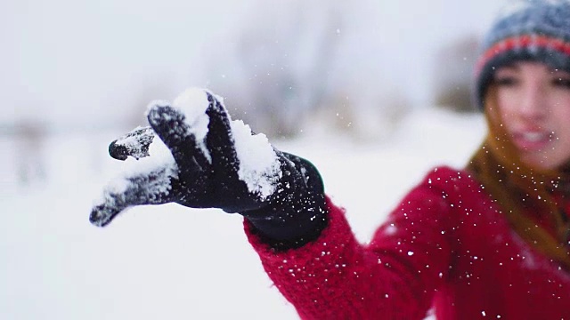 年轻快乐美丽的红发女人有一个与雪在她的手套在慢动作的乐趣视频素材