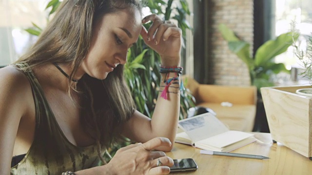 年轻漂亮的女人在咖啡馆用智能手机视频素材