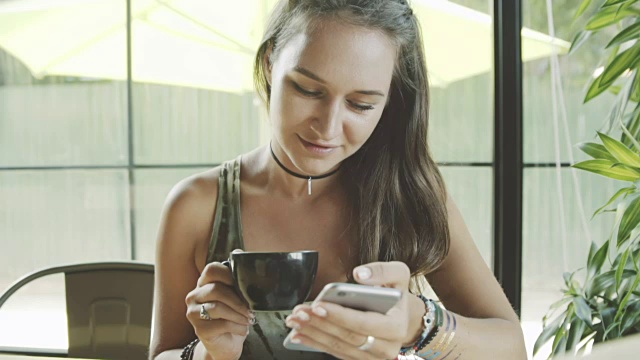 年轻漂亮的女人在咖啡馆用智能手机视频素材