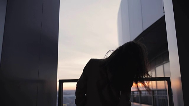 在摩天大楼上抛掷头发的女人剪影视频素材画面1
