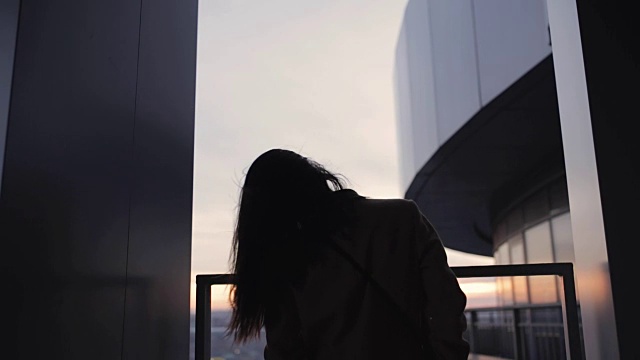 在摩天大楼上抛掷头发的女人剪影视频素材画面2