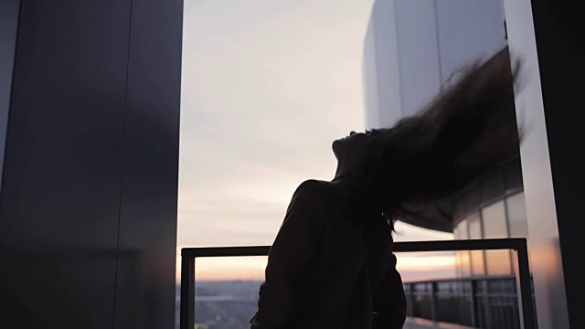 在摩天大楼上抛掷头发的女人剪影视频素材画面3