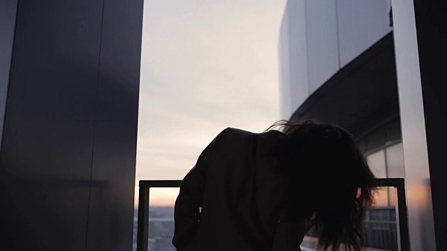 在摩天大楼上抛掷头发的女人剪影视频素材画面4