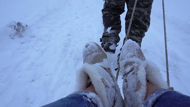 一个男人在雪地里用雪橇推着一个女孩视频素材