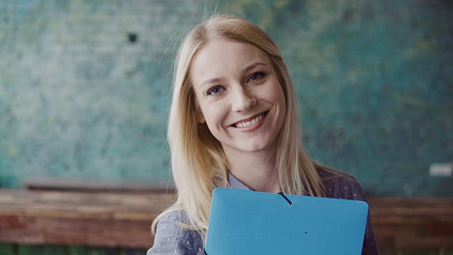 年轻白种金发女人的肖像看着照相机和微笑在现代办公室。工作上成功的员工视频素材画面3