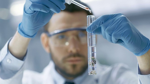 在一个现代实验室科学家通过在试管中使用滴管和植物合成化合物进行实验。视频素材画面1