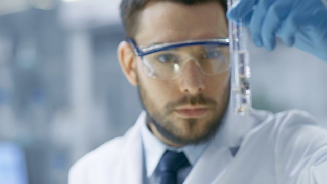 在一个现代实验室科学家通过在试管中使用滴管和植物合成化合物进行实验。视频素材画面4