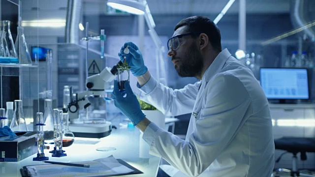 在现代实验室研究中，科学家用有机材料进行实验。他用吸管把肥料滴进装有植物的试管中。视频素材画面4
