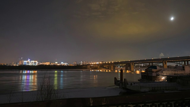 夜晚，新西伯利亚市的一座桥横跨融化的河流。时间流逝视频素材