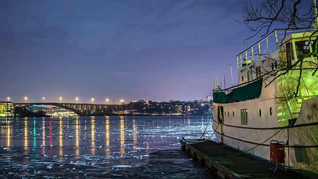 夜间的桥和冰冻的海湾4K时间流逝。码头和船，灯光反射在冰上视频素材