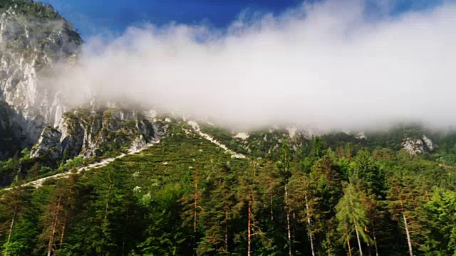 奥地利美丽的阿尔卑斯山。山峰上的云被森林覆盖着。行驶中的汽车窗外的景色视频素材