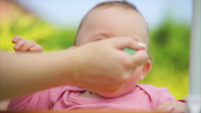 一个小而有趣的孩子在户外吃着我妈妈勺子里的粥视频素材画面4