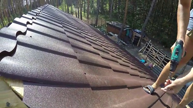 屋顶工用螺钉紧固金属屋面材料。视频素材画面1