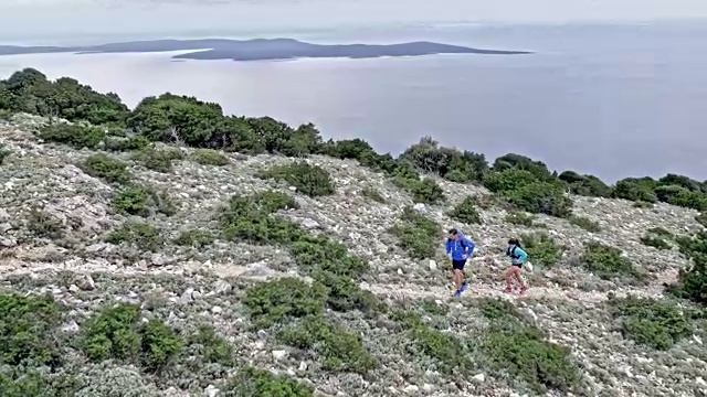 空中男人和女人跑上岩石山路俯瞰大海视频素材