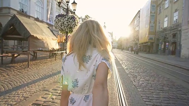 日落时分，年轻女子拉着男友穿过城市街道。快乐女友让她的男人跟着她去城里。视频素材画面1