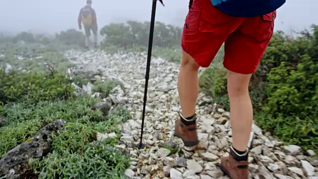 一位女性徒步者在浓雾中跟在她的女性朋友后面下山视频素材