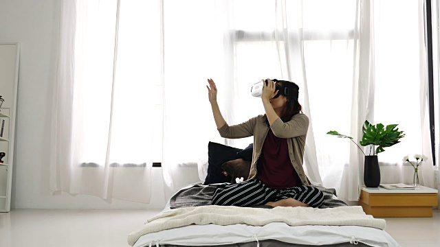 女人在卧室玩虚拟现实耳机视频素材画面3