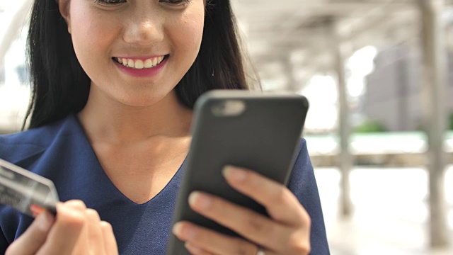 靠近女人的手使用手机和拿着信用卡在户外视频素材画面1