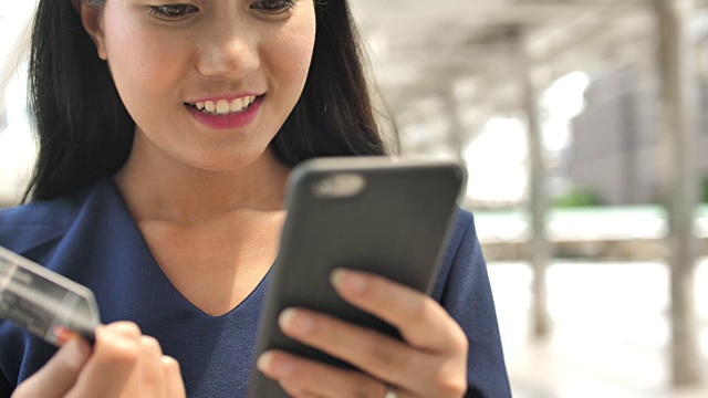 靠近女人的手使用手机和拿着信用卡在户外视频素材画面2