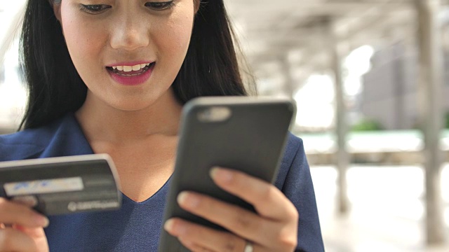 靠近女人的手使用手机和拿着信用卡在户外视频素材画面3