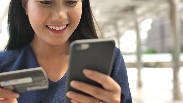 靠近女人的手使用手机和拿着信用卡在户外视频素材画面4