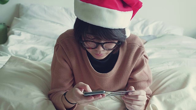 亚洲女性在客厅里用手拿着手机和信用卡。视频素材画面2