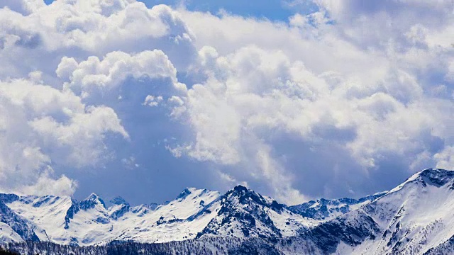 在阳光明媚的冬日户外，云的时间流逝由风的能量与雪山移动视频下载