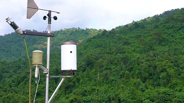 气象气象站天线与气象传感器，灰色多云天空和森林背景。视频下载