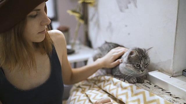 漂亮的年轻女人和小猫在家。宠物猫和年轻的主人一起放松视频素材