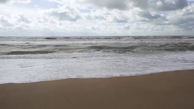 风暴的波浪在云的阴影下拍打着海岸视频素材