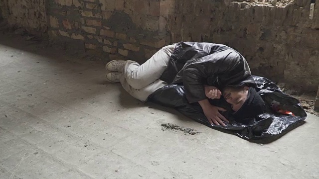 无家可归者睡在废弃建筑的垃圾袋上视频素材画面4