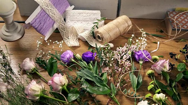 从上往下看:花店摆放鲜花、剪子、胶带、装饰纸等花束工具的木桌。Slowmotion拍摄视频素材画面1