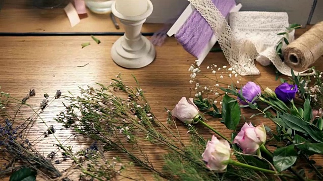 从上往下看:花店摆放鲜花、剪子、胶带、装饰纸等花束工具的木桌。Slowmotion拍摄视频素材画面4