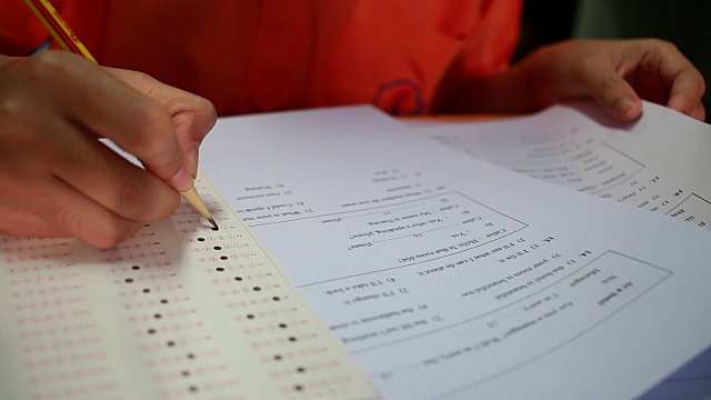 学生在考试时拿着橡皮、考场、写答案的光学形式在高中教室里，在课堂上坐在一排排的座位上进行考试的观点，教育素养观念。视频素材