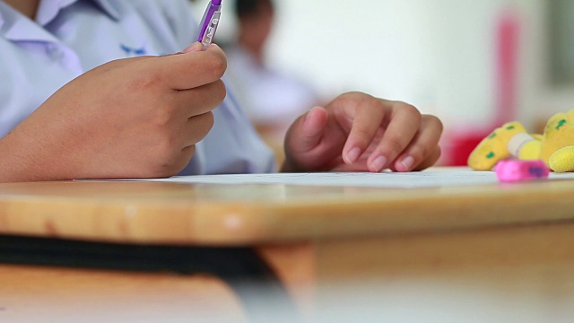 学生在考试时拿着橡皮、考场、写答案的光学形式在高中教室里，在课堂上坐在一排排的座位上进行考试的观点，教育素养观念。视频素材