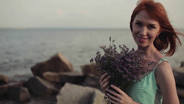 美丽性感的女孩与鲜花在阳光明媚的天气在大海的背景视频素材