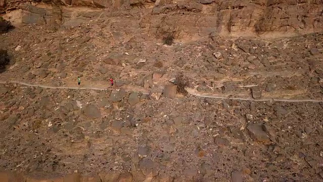 两名越野赛选手在峡谷上方的山道上冲刺视频素材画面2