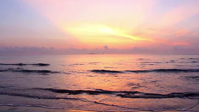 早晨的阳光随着海浪慢慢地溅在沙滩上。热带海滩宁静的田园风光。视频素材