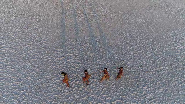 从空中俯瞰，四名圣布须曼人排成纵队，穿越广阔的博茨瓦纳Makgadikgadi pan视频素材画面1