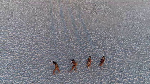 从空中俯瞰，四名圣布须曼人排成纵队，穿越广阔的博茨瓦纳Makgadikgadi pan视频素材画面2