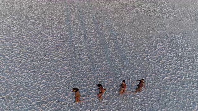 从空中俯瞰，四名圣布须曼人排成纵队，穿越广阔的博茨瓦纳Makgadikgadi pan视频素材画面3
