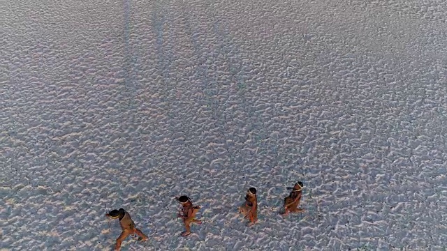 从空中俯瞰，四名圣布须曼人排成纵队，穿越广阔的博茨瓦纳Makgadikgadi pan视频素材画面4