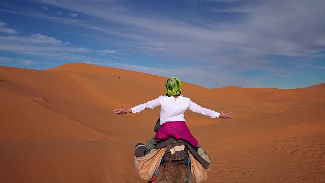 沙漠之旅。女人喜欢骑骆驼视频素材画面4