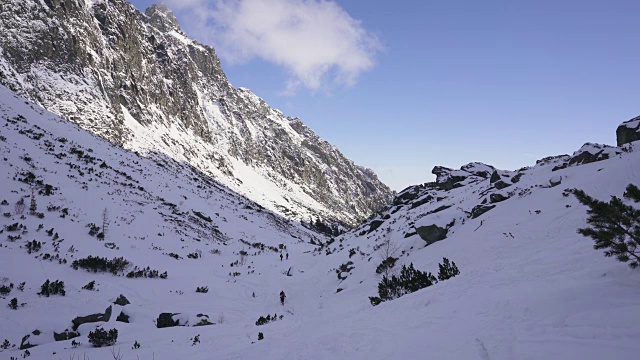 在寒冷的阳光明媚的天气里，滑雪游览覆盖在雪中的岩石山脉景观视频素材